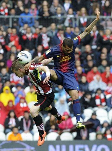 Barcelona's Dani Alves (R) jumps for the ball with Athletic Bilbao's Iker Muniain in Bilbao on April 27, 2013